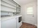 Functional laundry area equipped with washer, dryer, storage shelves, and exterior access at 7024 Rockledge Dr, Charlotte, NC 28210