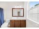 Bright bathroom featuring a wood-trimmed mirror, vanity, toilet, and a large window at 705 Brown Creek Dr, Matthews, NC 28104