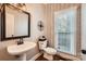 Cozy powder room features stylish wallpaper, dark wood floors, and an updated vanity with a decorative mirror at 7316 Versailles Ln, Charlotte, NC 28277