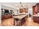 Open kitchen with wood cabinets, granite counters, island with seating, and stainless steel appliances at 7316 Versailles Ln, Charlotte, NC 28277