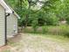Backyard view with a quaint house exterior, gravel area, and lush trees at 803 E 13Th St, Kannapolis, NC 28083