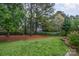Well-maintained backyard featuring green grass, mature trees, and neat landscaping at 942 Pelican Bay Dr, Pineville, NC 28134