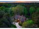 Aerial view of a luxury home surrounded by lush green forest at dusk at 10723 Green Heron Ct, Charlotte, NC 28278