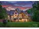 Expansive backyard view showcasing the multi-story home with wood and stone elements and a covered patio at 10723 Green Heron Ct, Charlotte, NC 28278