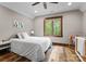 Cozy bedroom features a ceiling fan, white comforter, wood trim window, and hardwood floors at 10723 Green Heron Ct, Charlotte, NC 28278