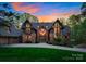 Spectacular home featuring stone and wood exterior, grand windows, lush landscaping, and a spacious driveway at 10723 Green Heron Ct, Charlotte, NC 28278