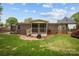 A brick home's backyard features a lawn, wooden deck, and screened-in porch under a blue sky with scattered clouds at 1113 Urban Pl, Charlotte, NC 28209