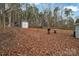 Leaf-covered backyard features mature trees, shed, wooden barrels, and chainlink fencing at 140 Wandering Ln, Bessemer City, NC 28016