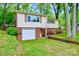 Split-level home features a front-entry garage, mature trees, and colorful shrubs enhancing the curb appeal at 1409 Sherwood Dr, Kannapolis, NC 28081