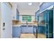 Well-lit kitchen boasts blue cabinets, stainless steel sink, and modern appliances, offering functionality and style at 1409 Sherwood Dr, Kannapolis, NC 28081