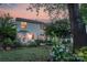 Landscaped backyard with patio, mature trees, and flowering shrubs at sunset at 16524 Kettlewell Ln, Charlotte, NC 28277