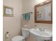 Powder room featuring a pedestal sink, decorative mirror, and neutral wall paint at 16524 Kettlewell Ln, Charlotte, NC 28277