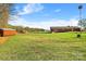 Expansive backyard featuring a well-maintained lawn, outbuildings, and mature trees under a partly cloudy sky at 173 Chestnut Grove Rd, Statesville, NC 28625