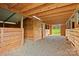 Spacious barn interior with wooden stalls, straw flooring, and an open doorway overlooking a green pasture at 173 Chestnut Grove Rd, Statesville, NC 28625