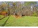 Enclosed chicken coop on a lush green lawn bordered by trees, next to a small wooden shed at 173 Chestnut Grove Rd, Statesville, NC 28625
