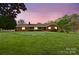 A charming brick home features a lush green lawn and a warm, inviting ambiance at dusk at 173 Chestnut Grove Rd, Statesville, NC 28625