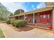 Inviting brick home features a charming front porch with red door, classic columns, and manicured landscaping at 173 Chestnut Grove Rd, Statesville, NC 28625