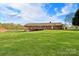 Back of brick home with a large, grassy yard, a deck, and mature trees offering privacy at 173 Chestnut Grove Rd, Statesville, NC 28625