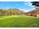 Back of brick home with sprawling green lawn, complete with a deck, garden area, and storage shed at 173 Chestnut Grove Rd, Statesville, NC 28625