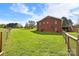 Brick home showcasing a large, grassy backyard, complemented by a deck and a charming fence at 173 Chestnut Grove Rd, Statesville, NC 28625