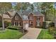 Classic brick home featuring arched windows, black shutters, manicured landscaping, and a welcoming driveway at 18418 Turnberry Ct, Davidson, NC 28036