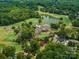Aerial view of a meticulously maintained golf course and country club nestled amongst lush greenery and a serene lake at 18418 Turnberry Ct, Davidson, NC 28036