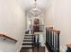 Elegant staircase with dark wood steps and ornate chandelier, leading to a bright, inviting hallway at 2030 Radcliffe Ave, Charlotte, NC 28207