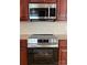 Close up of stainless oven, microwave, cherry cabinets, and granite countertops at 216 Harrison Ln # 4, Locust, NC 28097