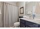 Stylish bathroom features a blue vanity and tub with a gray and white striped shower curtain at 2610 Creek Manor Dr, Waxhaw, NC 28173