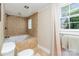 Bathroom with a tiled jacuzzi tub, neutral paint, and a bright window with privacy curtain at 2909 Park Rd, Charlotte, NC 28209