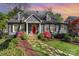 Charming gray brick home with a red door, dormer windows, and beautifully landscaped front yard with a stone walkway at 2909 Park Rd, Charlotte, NC 28209