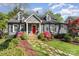 Charming gray brick home with a red door, dormer windows, and beautifully landscaped front yard with a stone walkway at 2909 Park Rd, Charlotte, NC 28209