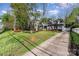 View of a gray brick home and driveway through mature trees with a grass yard and well manicured landscaping at 2909 Park Rd, Charlotte, NC 28209
