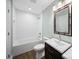 Bathroom with tiled shower and bath, dark vanity, and bright modern finishes at 3677 Antioch Church Rd, Matthews, NC 28104