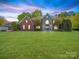 Beautiful brick and stone home with lush lawn and manicured landscaping under a picturesque sunset sky at 3677 Antioch Church Rd, Matthews, NC 28104