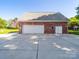Detached brick garage with multiple white doors and ample parking space on a paved driveway at 3677 Antioch Church Rd, Matthews, NC 28104