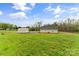 A charming home with a shed is set on a spacious grassy lawn against a backdrop of trees and a blue sky at 391 Springs East Rd, Lincolnton, NC 28092