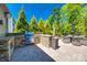 Outdoor kitchen with stainless steel grill, stone counter, and patio seating overlooking lush greenery at 4032 Wild Turkey Ln, Indian Land, SC 29707