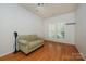 Bright bedroom with hardwood floors, a sofa, and a window with plantation shutters at 4133 Carl Parmer Dr, Harrisburg, NC 28075