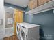 A modern laundry room features a stackable washer and dryer, shelving, and a sliding barn door at 4754 Hedgemore Dr # O, Charlotte, NC 28209