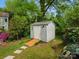 A quaint shed sits in a lush backyard, surrounded by greenery and a tree stump at 512 Secrest Ave, Belmont, NC 28012