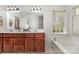 Spacious bathroom featuring a double vanity with warm wood cabinets and a soaking tub by the window at 591 Highland Ridge Rd, Mooresville, NC 28115
