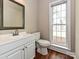 Well-lit bathroom with white vanity, mirror and toilet plus wood flooring and a window at 6112 Swanston Dr, Charlotte, NC 28269