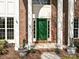 Inviting green front door with white columns, brick accents, and 'Welcome' potted plants for a warm entry at 6112 Swanston Dr, Charlotte, NC 28269