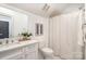 Bright bathroom with marble vanity, white fixtures, and a shower with a neutral-colored shower curtain at 728 Brookside Ave, Charlotte, NC 28203