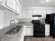 Bright kitchen with white cabinets, granite countertops, and stainless steel sink and black appliances at 7301 Pebblestone Dr # F, Charlotte, NC 28212