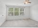 Bright bedroom with three windows, neutral carpet, ceiling fan, and closet at 9612 Eagle Feathers Dr, Charlotte, NC 28214
