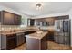 Kitchen features stainless steel appliances, dark wood cabinets, tile backsplash, and a center island at 9612 Eagle Feathers Dr, Charlotte, NC 28214