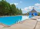 A pristine pool with a blue building and lounge chairs, set against a backdrop of lush trees under a clear blue sky at 9612 Eagle Feathers Dr, Charlotte, NC 28214