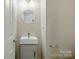 Modern half bath features a pedestal sink with a round mirror and light fixture at 1014 Sandbox Cir, Indian Trail, NC 28079